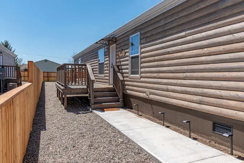 Comfy Lodge House: Exterior side of the home with deck steps and gravel path