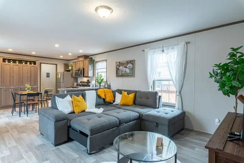 Cozy 3BR Lodge: Open living room with sectional sofa and kitchen beyond