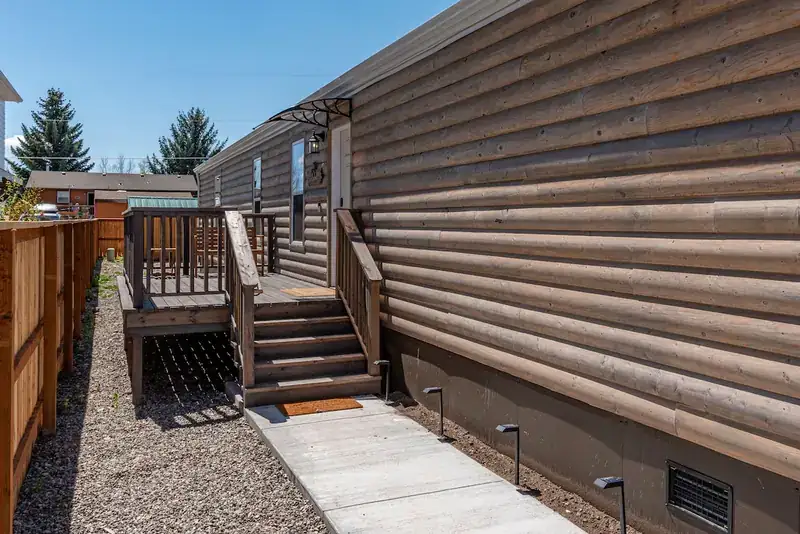 Cozy 3BR Lodge: Exterior side of the home with deck steps and gravel path