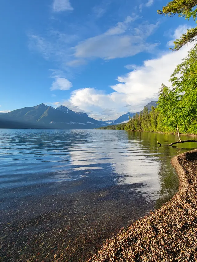 Calm lake reflecting sky and mountains in Glacier