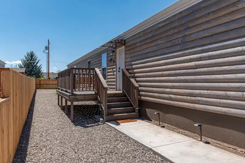 Sky 3BR Lodge: Exterior side of the home with deck steps and gravel path