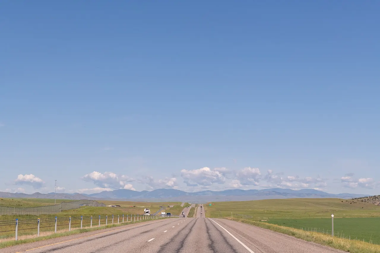 Main road through Manhattan, Montana with farmland and mountains