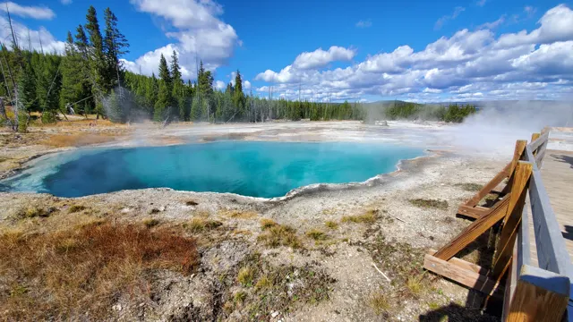 Turquoise hot spring pool beside a wooden boardwalk in Yellowstone